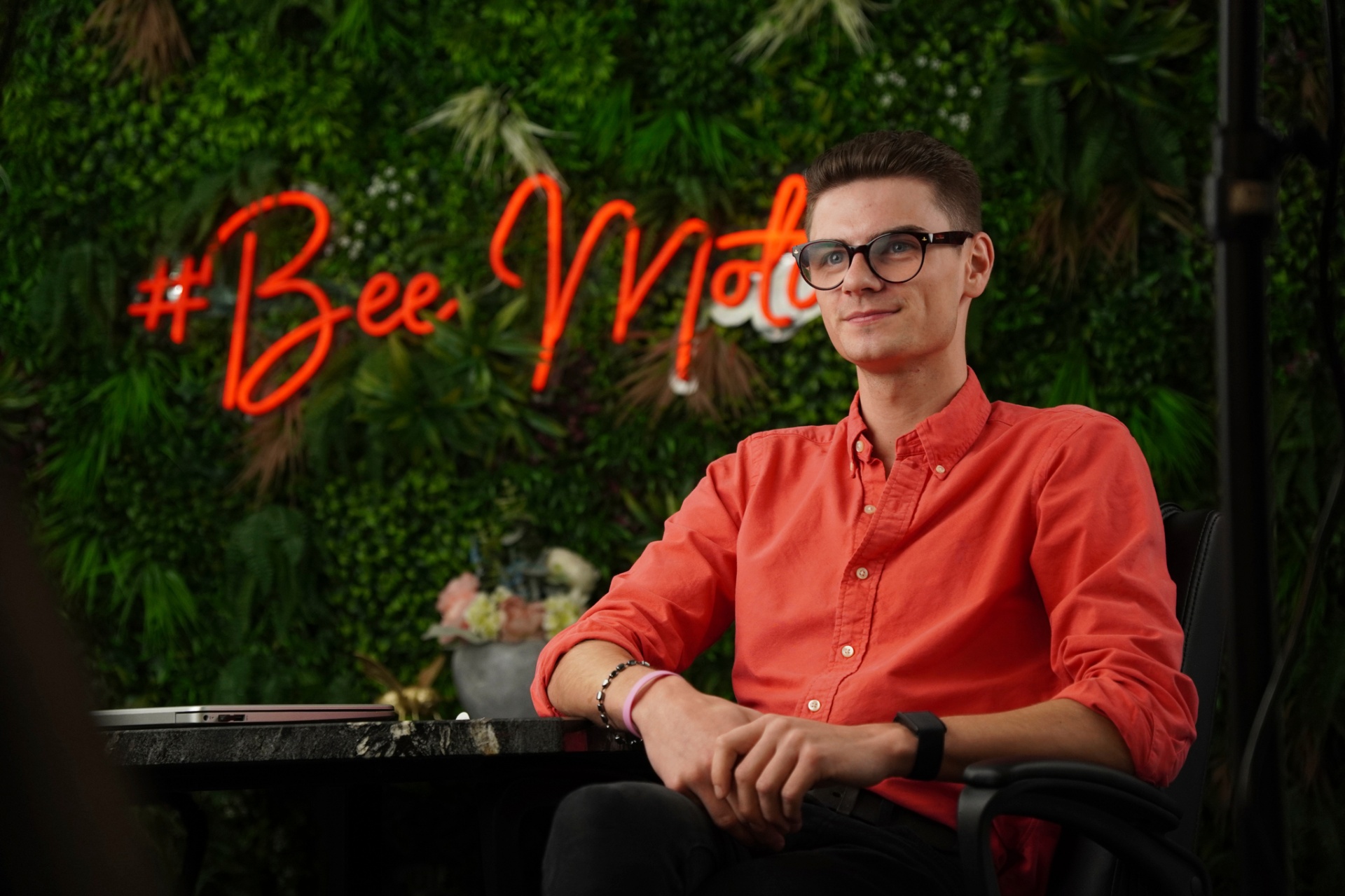 Bee Motion team member in front of the office neon sign